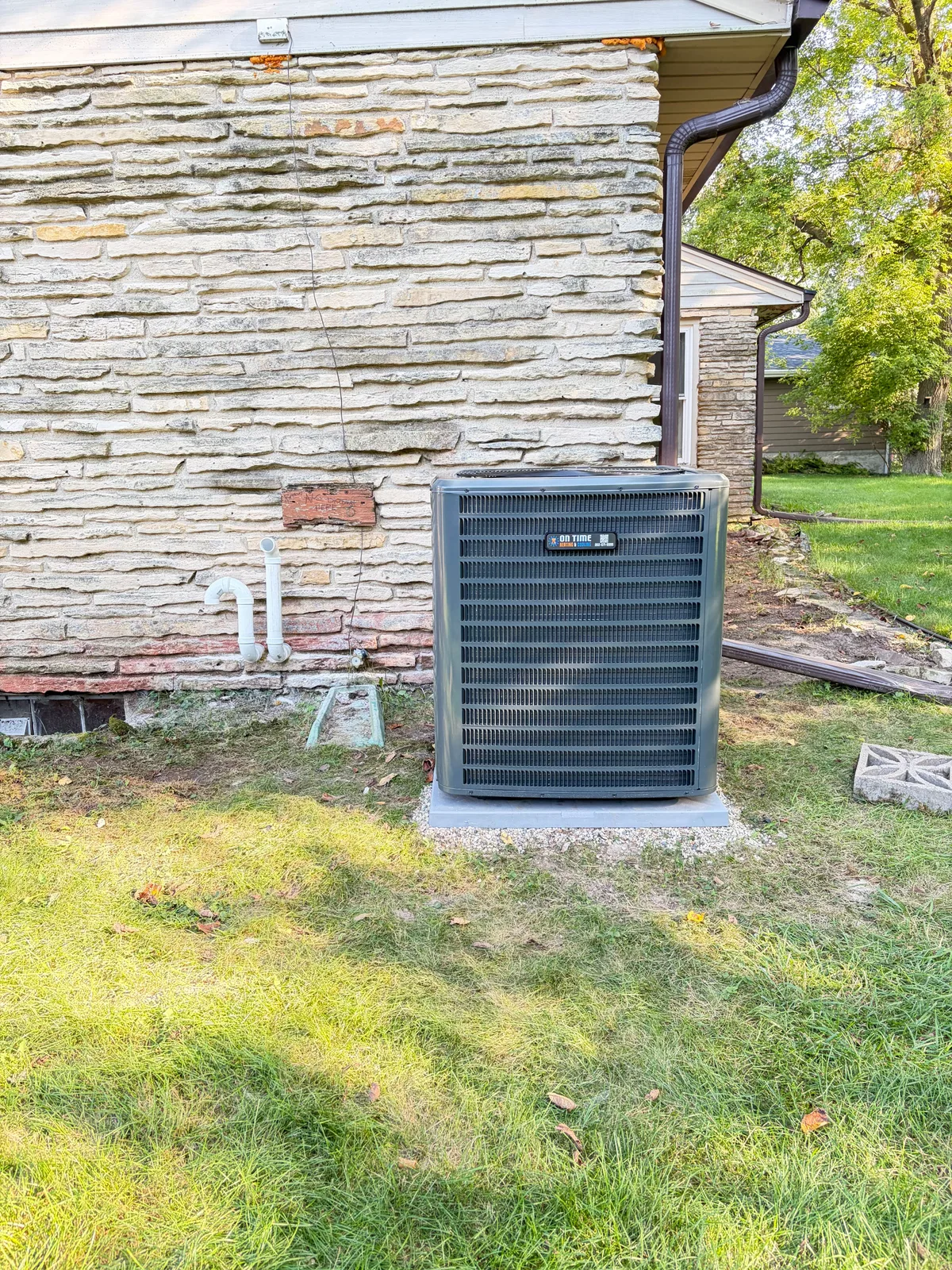 On Time Heating & Cooling air conditioner installed beside a stone house