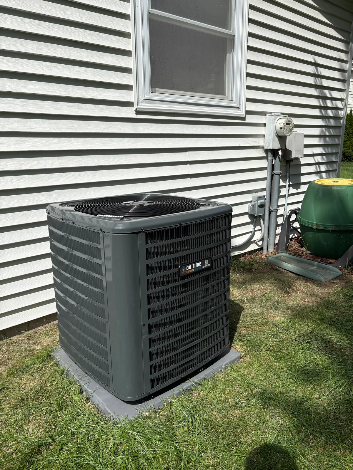 On Time Heating & Cooling air conditioner installed beside a home with white siding
