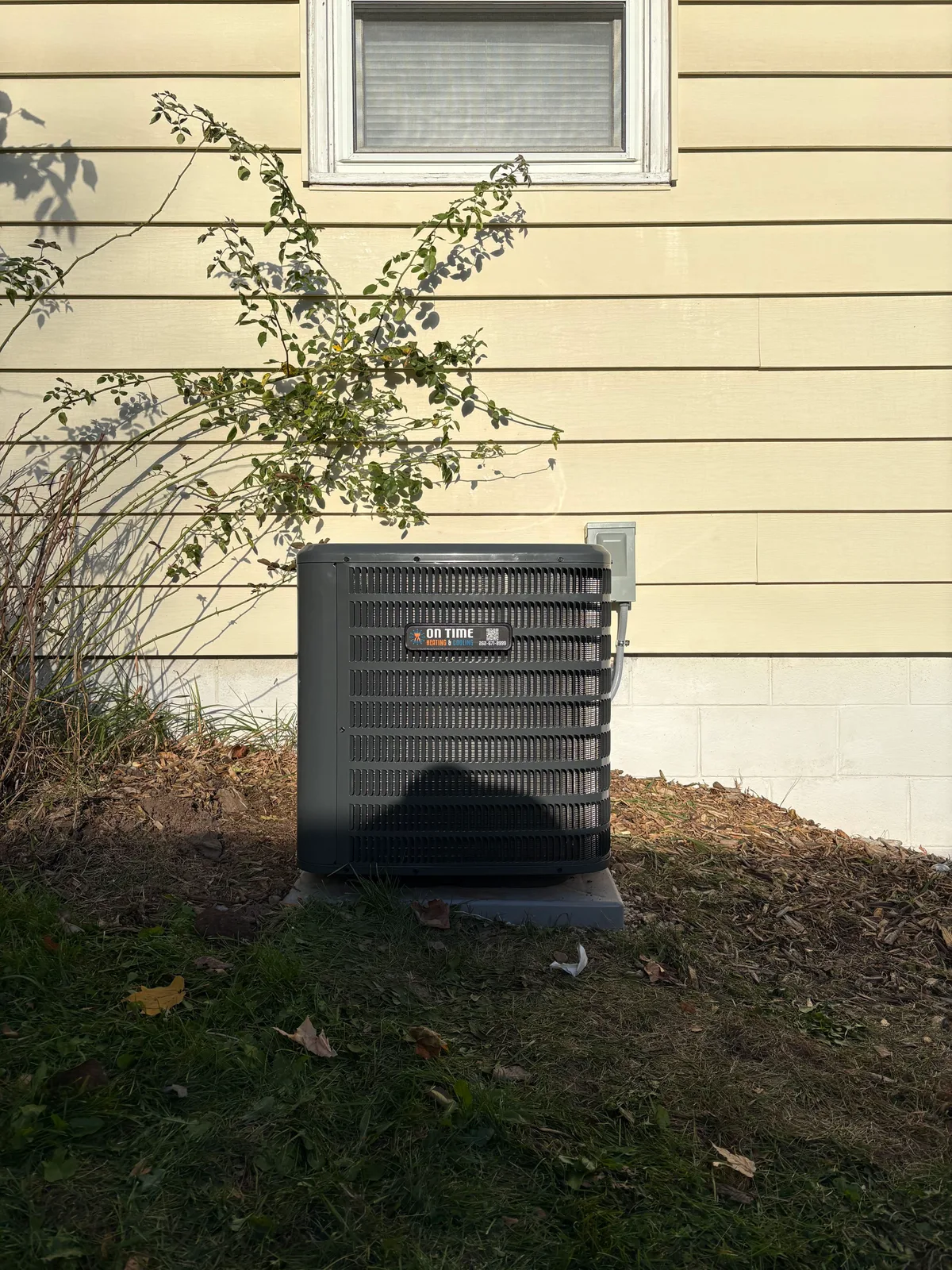 On Time Heating & Cooling air conditioner installed beside a home with yellow siding